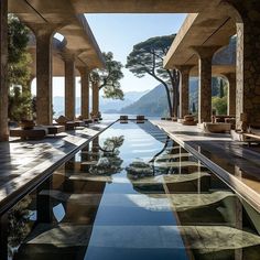 an outdoor swimming pool surrounded by stone pillars and columns with trees in the background,