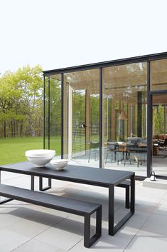 a table and bench sitting in front of a glass walled room with large sliding doors