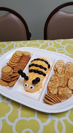 a white plate topped with crackers covered in cheese and black eyes next to other snacks