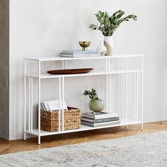 a white shelf with books and plants on it