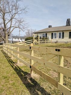 a wooden fence in front of a house with a tree on the other side of it