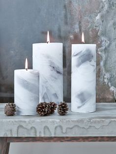 three white candles sitting on top of a table