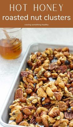 a pan filled with nuts and honey next to a glass of honey on the side