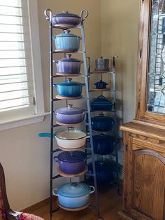 a tall metal shelf filled with blue and white dishes next to a wooden dresser in a room