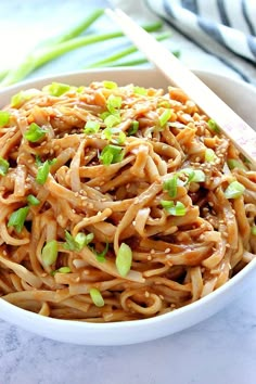 a white bowl filled with noodles and green onions