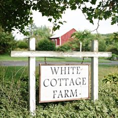 a white cottage farm sign sitting in the grass