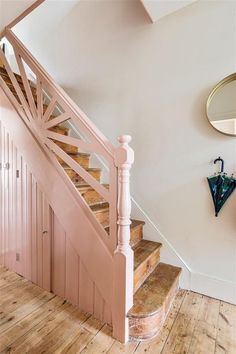 a wooden stair case next to a mirror on the wall in a room with white walls