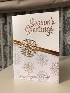 a white card with gold foiling and a snowflake on the front that says season's greetings