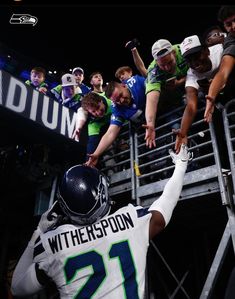 a group of people standing around each other in front of a football player with his hand on the back of another person's head