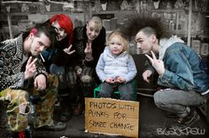 a group of people sitting next to each other in front of a store window holding signs