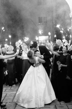 a bride and groom kissing in front of their guests with sparklers on the ground