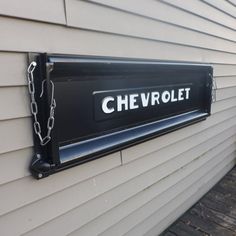 a chevrolet license plate mounted to the side of a house with chains hanging from it