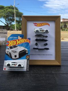 two hot wheels cars are in front of a wooden frame with a toy car on it