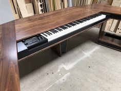 a piano sitting on top of a wooden table in a room filled with bookshelves