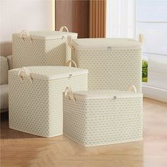 three white storage baskets sitting on top of a hard wood floor next to a couch