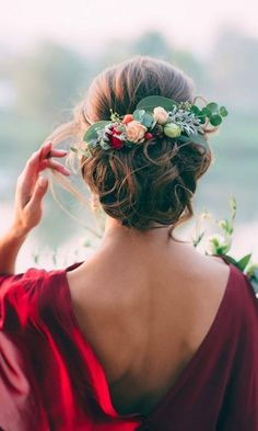 a woman in a red dress wearing a floral headpiece with greenery on her hair