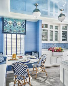 a kitchen with blue walls and white cabinets is pictured in this image, there are four chairs around the table