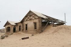 an old house is buried in sand on a cloudy day with no one around it