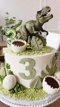 a dinosaur birthday cake is decorated with green and white frosting, including an egg shell