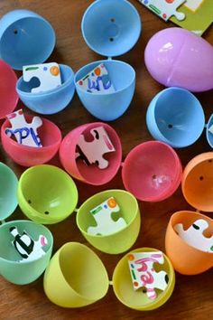 many different colored bowls and spoons on a wooden table with paper cut outs in the shape of animals