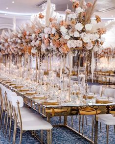 a long table with tall centerpieces filled with white flowers and gold candlesticks