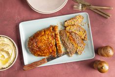 meatloaf and mashed potatoes on a plate next to an eggplant