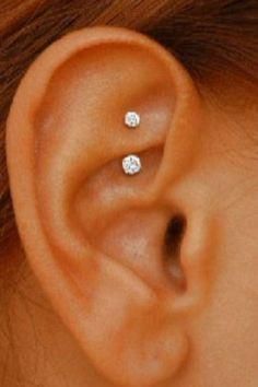 a woman's ear with two small white diamonds