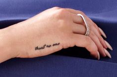 a woman's hand with a small tattoo on her left wrist that says, trust no one