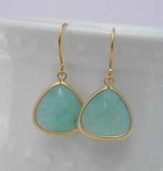 Gorgeous gold plated aqua mint blue glass fancy, teardrop charms hang from 14 karat gold plated earwires. These are the color of the Caribbean Sea and look terrific paired with the gold. The charms are 14mm with a 5mm thickness at the widest point, and earrings hang approximately one inch from the ear.Unless noted otherwise, we ship to the address listed in the PAYPAL transaction, so please make sure it is correct.Orders are shipped via USPS 1st class mail Gold Teardrop Earrings For Bridesmaid Gift, Aqua Mint, Mint Blue, Earrings In Gold, Caribbean Sea, Bride Bridal, The Caribbean, Bridal Wedding, Blue Glass