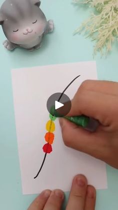 someone is doing something with colored crayons on paper and the cat is next to it