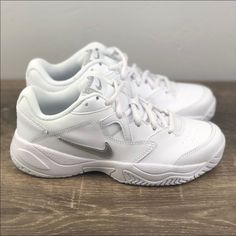 a pair of white nike shoes sitting on top of a wooden table