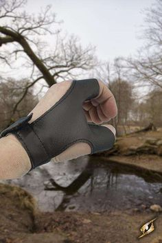 a hand that is holding something in it's right hand with trees and water in the background