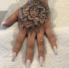 a woman's hand with an intricate tattoo on it