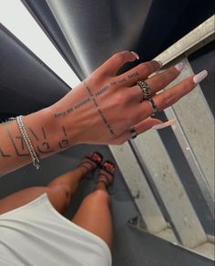 a woman's arm with tattoos on it and her hand in the air above her