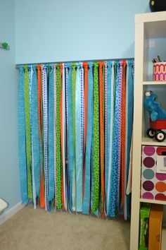 a room with blue walls and colorful streamers hanging from the wall in front of a bookshelf