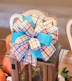 a blue bow on top of a wooden box with pumpkins in the background and a chair