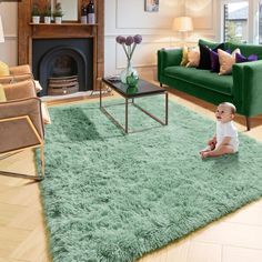 a baby sitting on the floor in front of a green rug