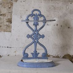 a blue metal object sitting on top of a cement floor next to a brick wall