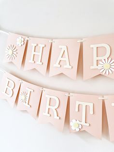 two pink happy birthday banners with flowers on them are hanging from a white wall next to each other