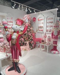 a room filled with pink and white christmas decorations, including a statue of a mouse