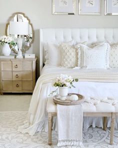 a bedroom with white furniture and pictures on the wall