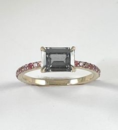 Cast in 18k white gold. A stunning gunmetal grey spinel gemstone faceted in a traditional emerald cut set in sharp stylized prongs. The band is cast in 18k white gold and features multi shade pink sapphire accent stones. - 18k white gold - .88ct emerald cut grey spinel - .33ctw pink purple sapphires Available in 18k white, 18k yellow and 18k rose gold inquire for platinum pricing. Most CM pieces can be made to order with alternate gemstones. Please inquire at cm@carlamorrison.com This Carla Morr Emerald Cut Pink Sapphire Ring In Fine Jewelry Style, Fine Jewelry Emerald Cut Pink Sapphire Ring, Modern Emerald Cut Sapphire Ring With Accent Stones, Emerald Cut Sapphire Ring With Rose Cut Diamonds, Emerald Cut Ruby Ring With Rose Cut Diamonds, Emerald Cut Pink Sapphire Ring, Spinel Gemstone, Pink Sapphire Ring, Purple Sapphire