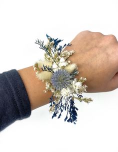 a person's hand with a bracelet made out of flowers and leaves on it