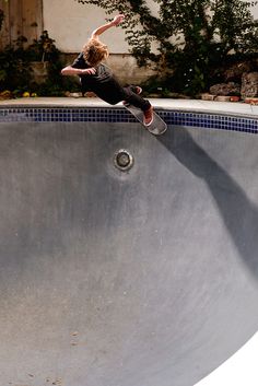 a person on a skateboard in the air above a pool