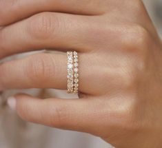 a woman's hand wearing a gold ring with three rows of diamonds on it