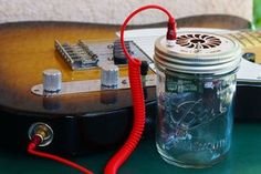 an electric guitar is plugged in to a mason jar with red cord and wires