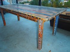 a table made out of old skis on top of a roof with the city in the background