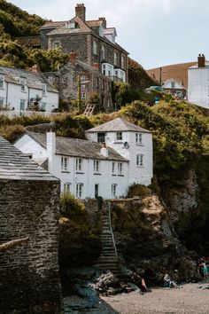 people are sitting on the beach in front of some white buildings and stairs leading up to them