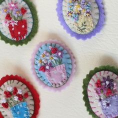 four handmade flower pots with flowers in them on a white surface and one is hanging from the wall