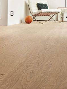 a living room with wood floors and white furniture in the background is an orange ball on the floor